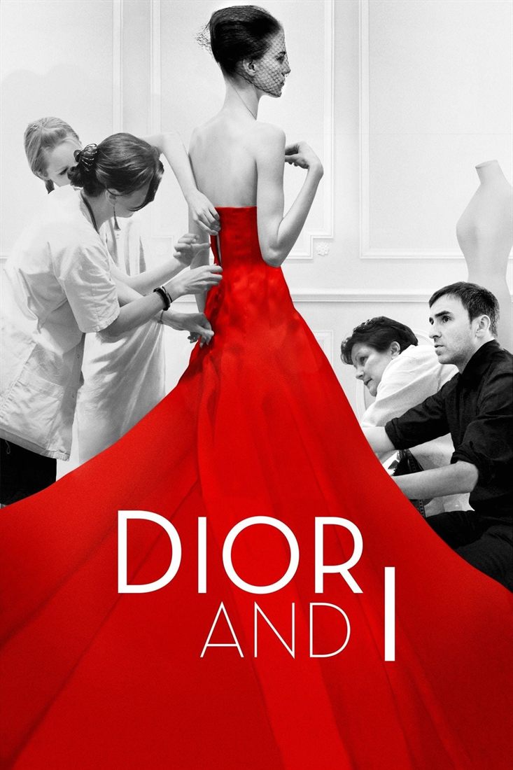 A model in a long red dress surrounded by seamstresses in a workshop.