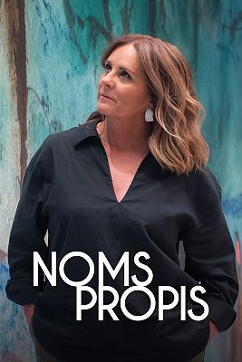 Presenter Anna Cler in a black blouse in front of a painted wall.